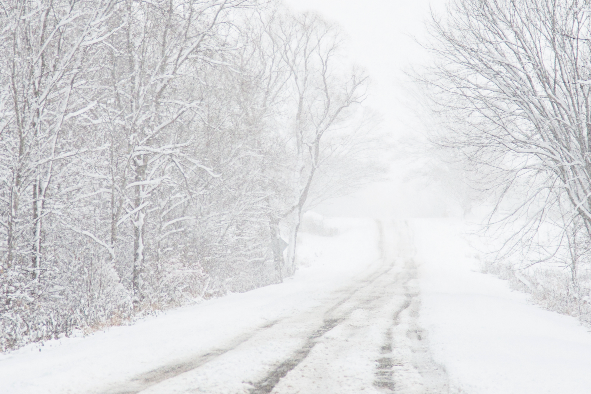 Image of a road that is partly snow covered in the wintertime