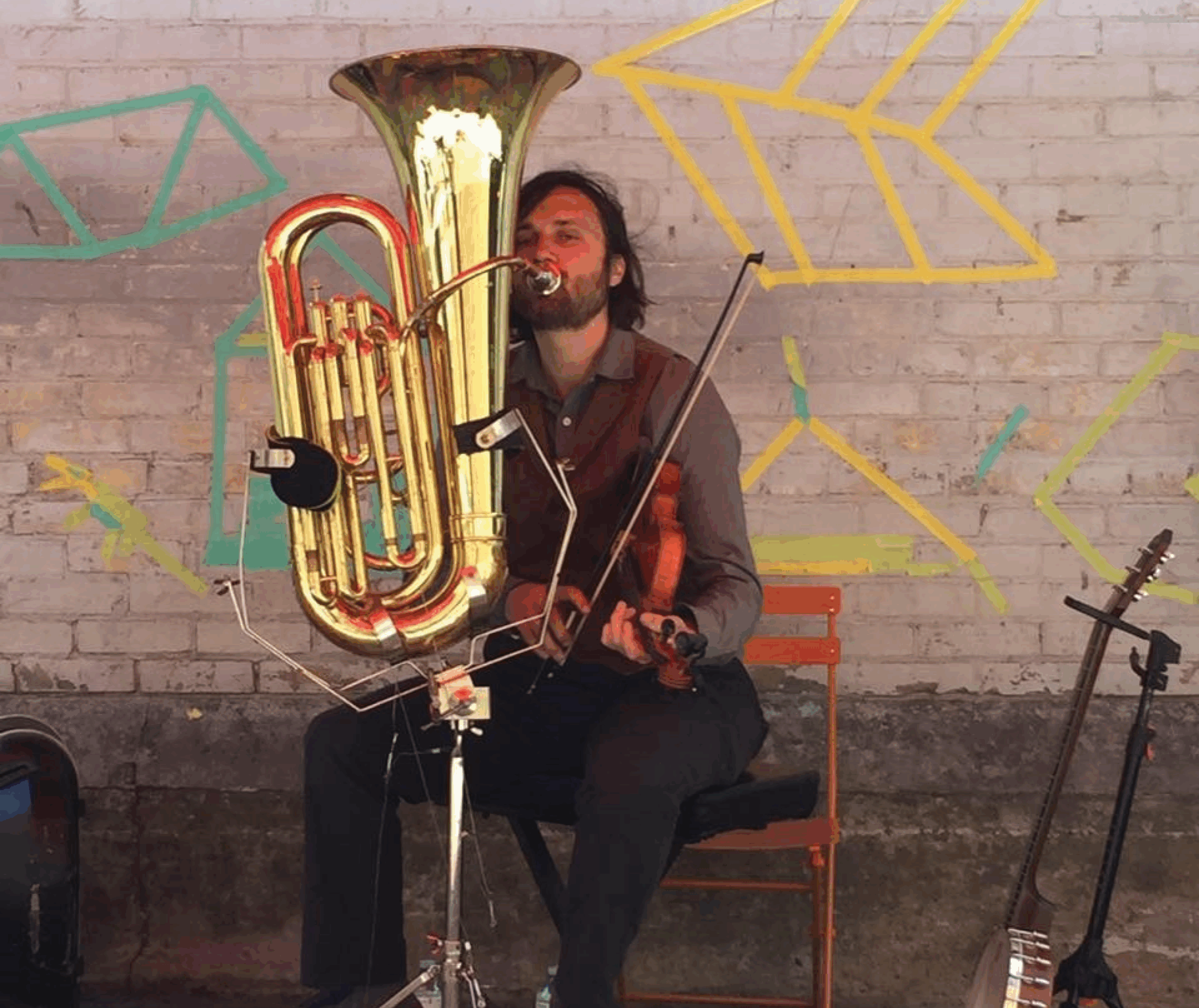 Photo of Dave Neigh sitting in a chair playing the tuba